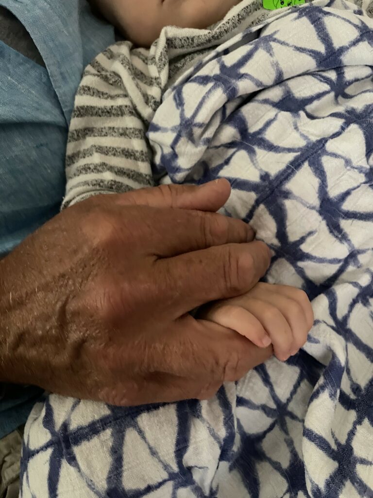 James holding his grandchild's hand